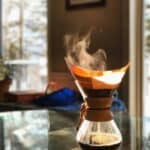 A glass brewer with steam rising from fresh coffee
