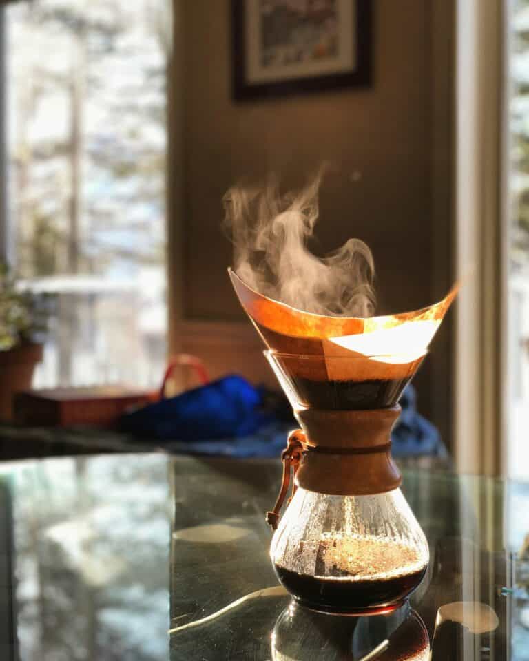 A glass brewer with steam rising from fresh coffee