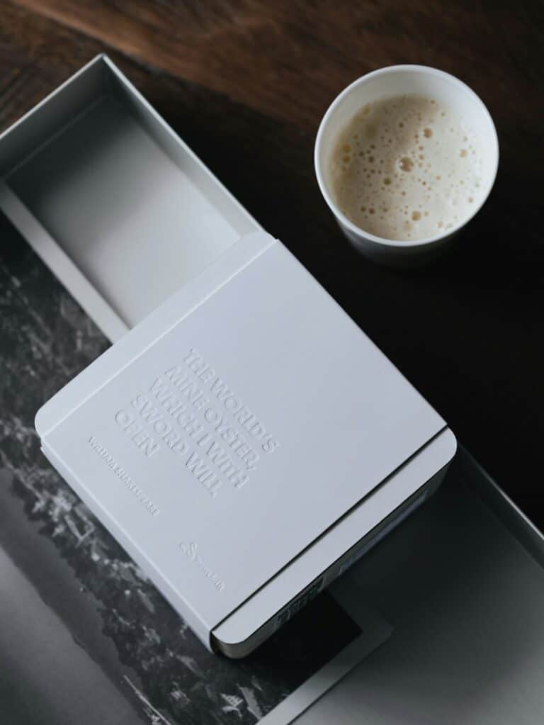 An embossed white gift box beside a cappuccino
