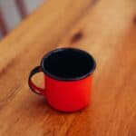 A red enamel mug on a wooden table