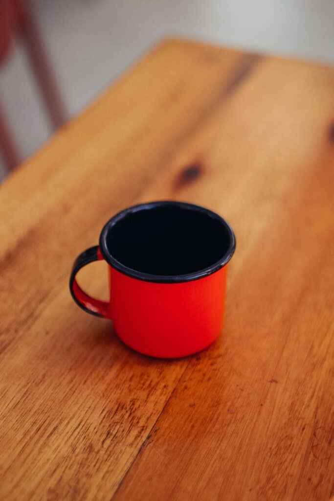 A red enamel mug on a wooden table