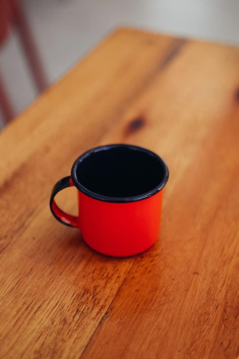A red enamel mug on a wooden table
