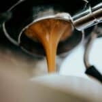 Espresso extracting from a portafilter into a white cup