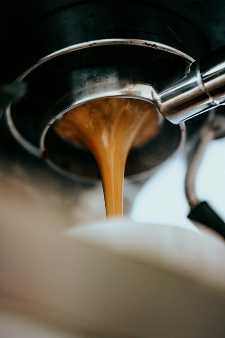 Espresso extracting from a portafilter into a white cup